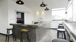Cocina moderna con una isla central, taburetes de bar, iluminación colgante y grandes ventanales con vistas a la ciudad.