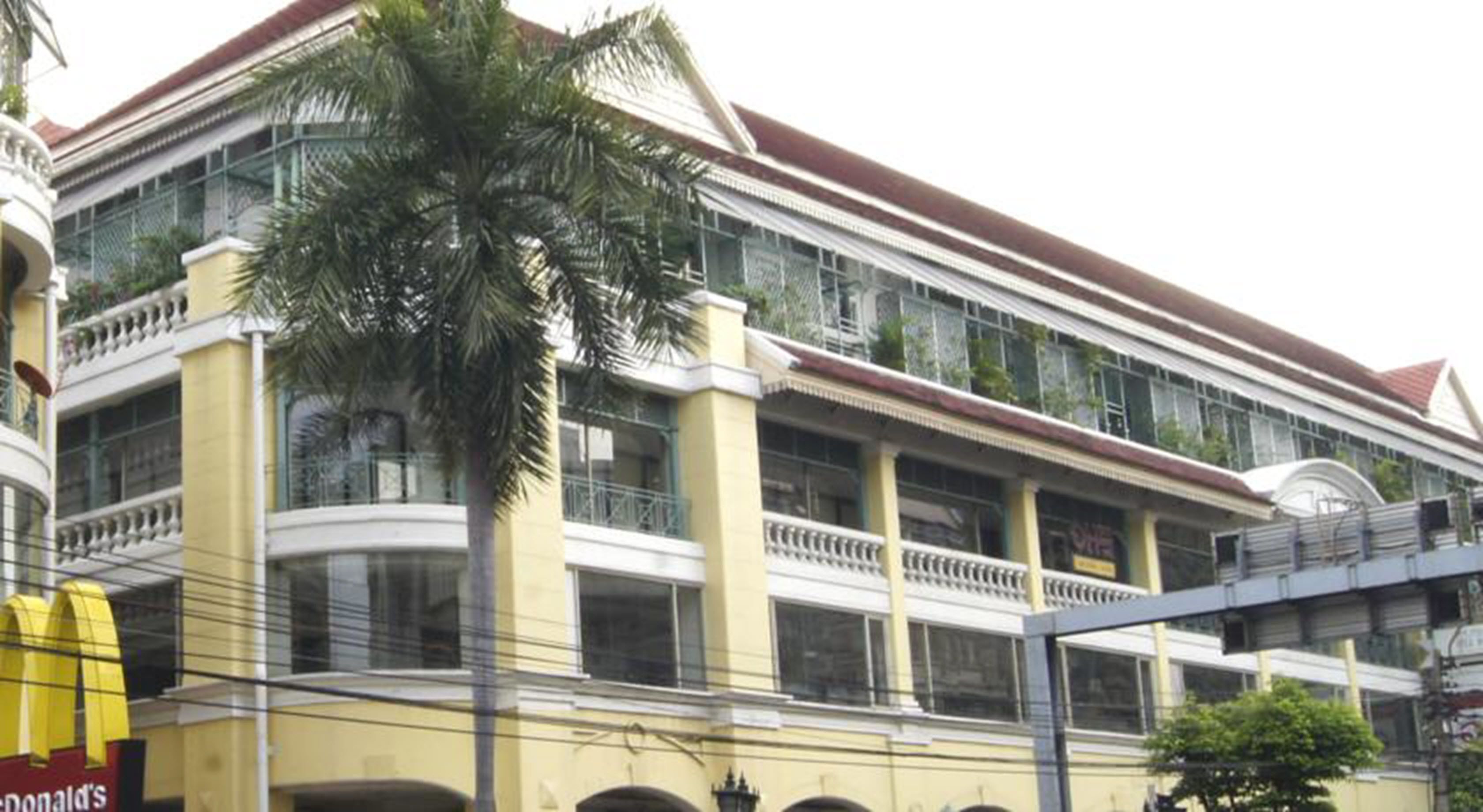 A multi-story building with balconies, a palm tree in front, and a McDonald's sign on the left.