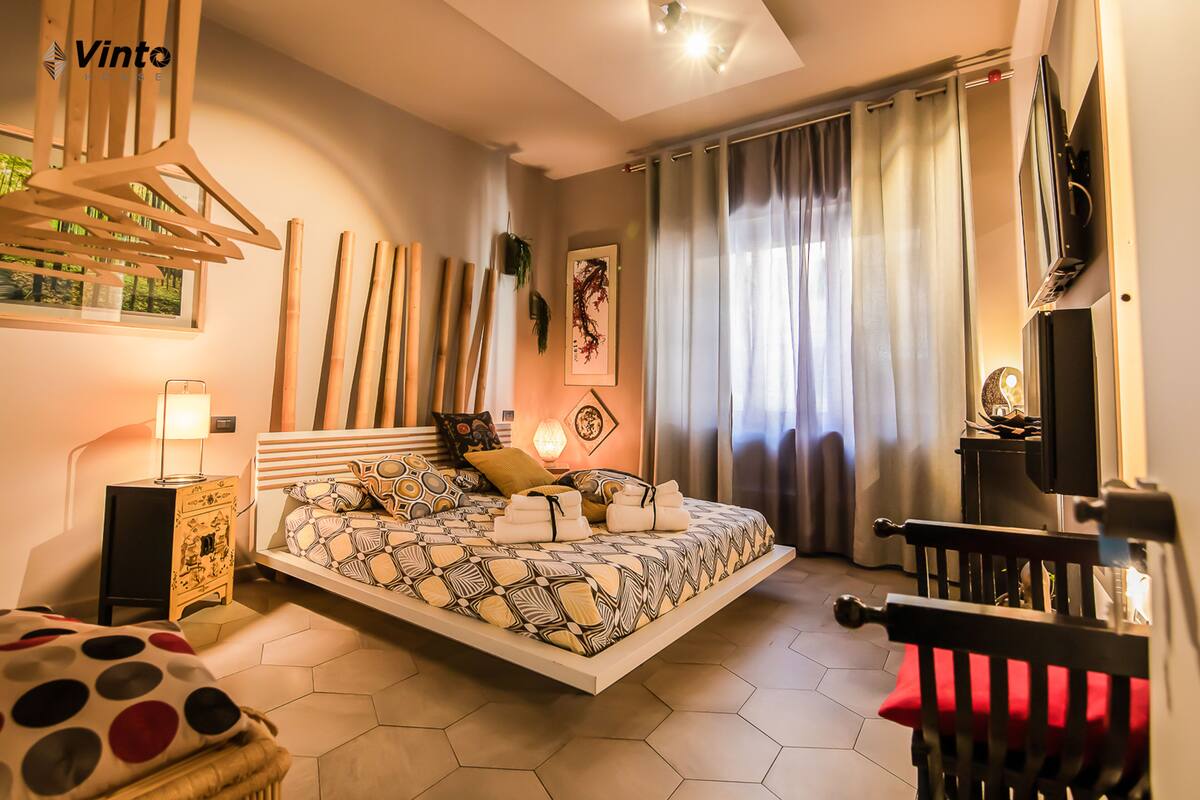 A modern bedroom with a floating bed, a wooden hanger, a TV, and a small side table.