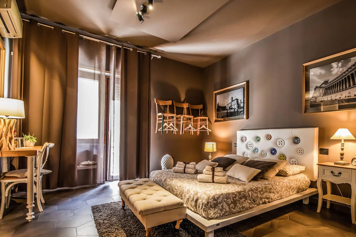 A bedroom with a large bed, bedside tables, a mirror, and a window with curtains.