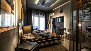 Een moderne slaapkamer met een groot bed, een bureau en een stoel. Er is een raam met gordijnen, een aan de muur bevestigde televisie en een plafondlamp.