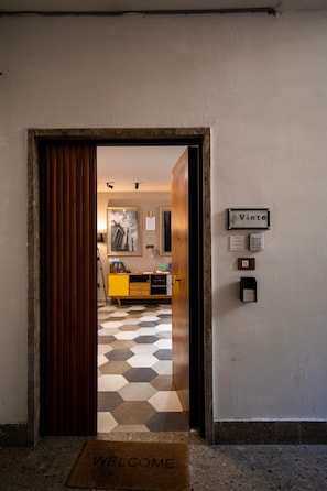 A hotel entrance with a checkered floor, a welcome mat, a wooden door, and a sign indicating the hotel name. - Vinto House Salerno (Salerno)