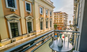 A balcony with a table, overlooking a street with buildings and a clear sky. - Vinto House Salerno (Salerno)