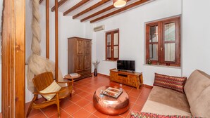 A living room with a sofa, wooden furniture, a television, and a large window. - Casa Sabbionara (Chania)