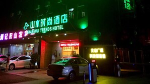 Een hotel met neonreclame, een parkeerplaats en een auto ervoor.