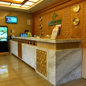 A hotel reception desk with a wooden panel design, multiple clocks, and a digital screen displaying room rates. - Shanshui Trends Hotel Pazhou Branch (Guangzhou)