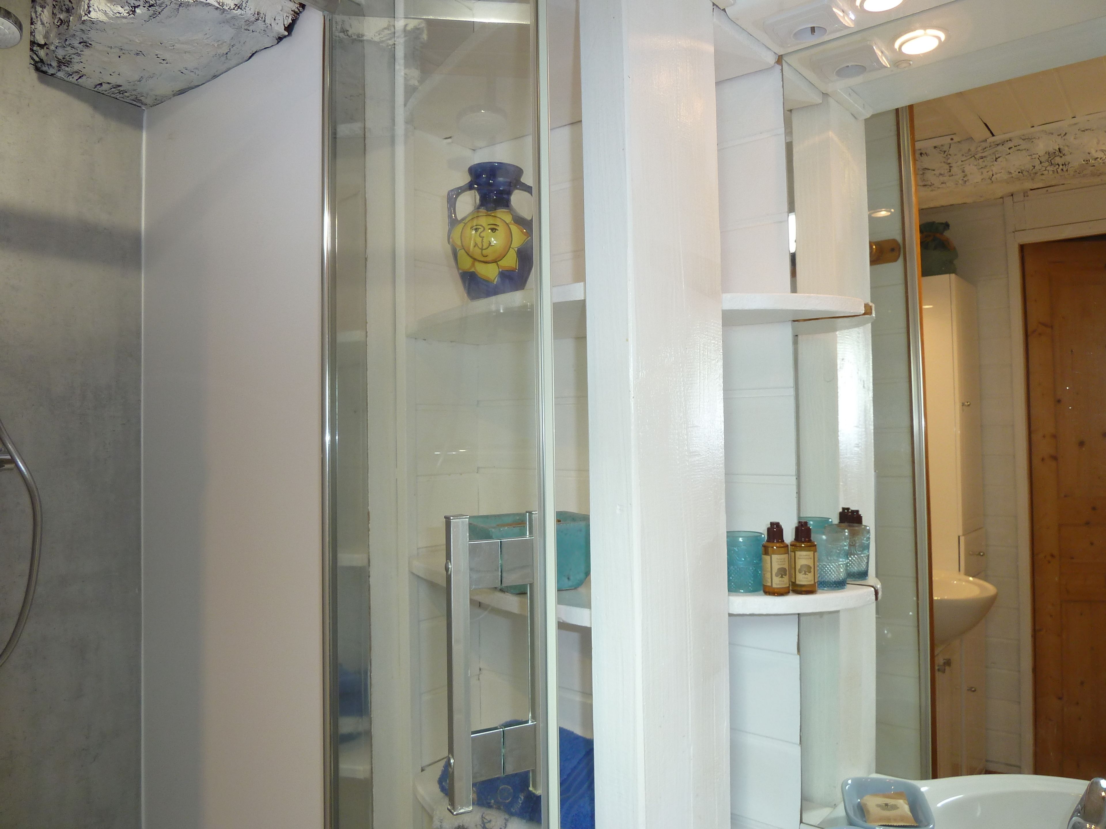 Un baño con mampara de vidrio, lavamanos y espejo.