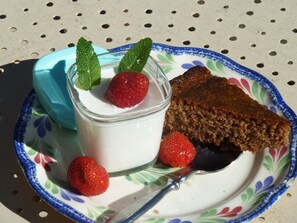A plate with a slice of cake, a glass of yogurt with strawberries and mint, and a spoon. - Les Bruyères du Mont (Ceaux)