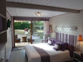Un dormitorio con cama, mesita de noche, lámpara y vistas al jardín a través de una puerta corrediza.