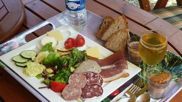 A meal tray with a variety of foods including bread, cheese, meats, and vegetables, along with a bottle of water and a glass of juice.