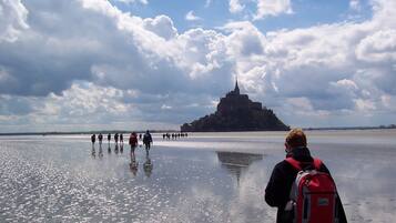 A group of people walking on a frozen body of water with a historic castle in the background.