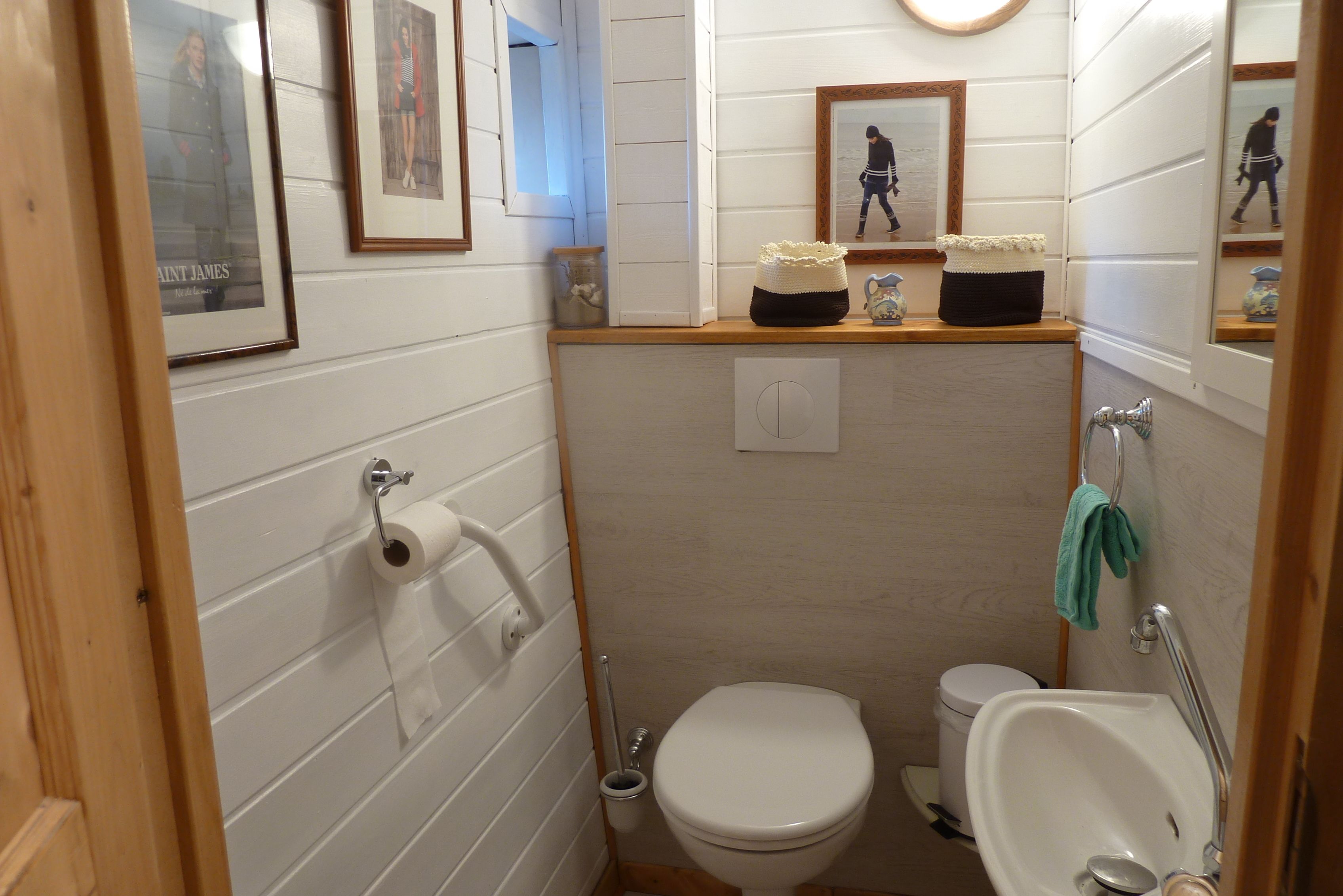 A compact bathroom with a toilet, sink, and framed pictures on the wall.