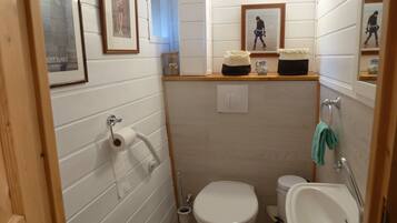 A compact bathroom with a toilet, sink, and framed pictures on the wall.