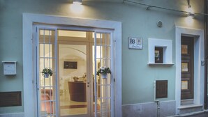A building with a large glass door entrance, a small window with a sign, and a wall-mounted light fixture. - B&B Portanuova (Vasto)