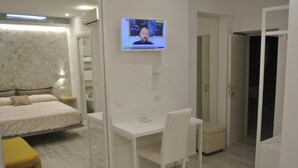 A modern bedroom with a bed, a desk, and a TV mounted on the wall. - B&B Portanuova (Vasto)