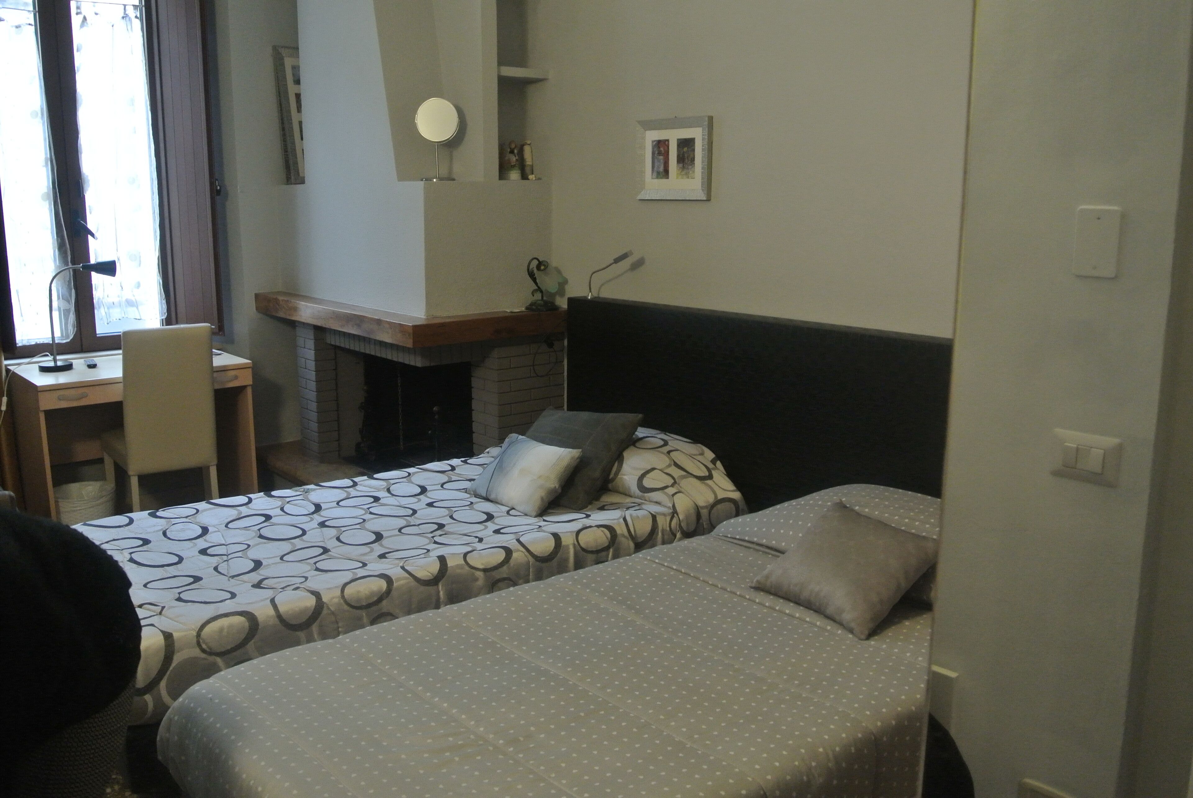 A bedroom with two beds, a desk, and a chair.