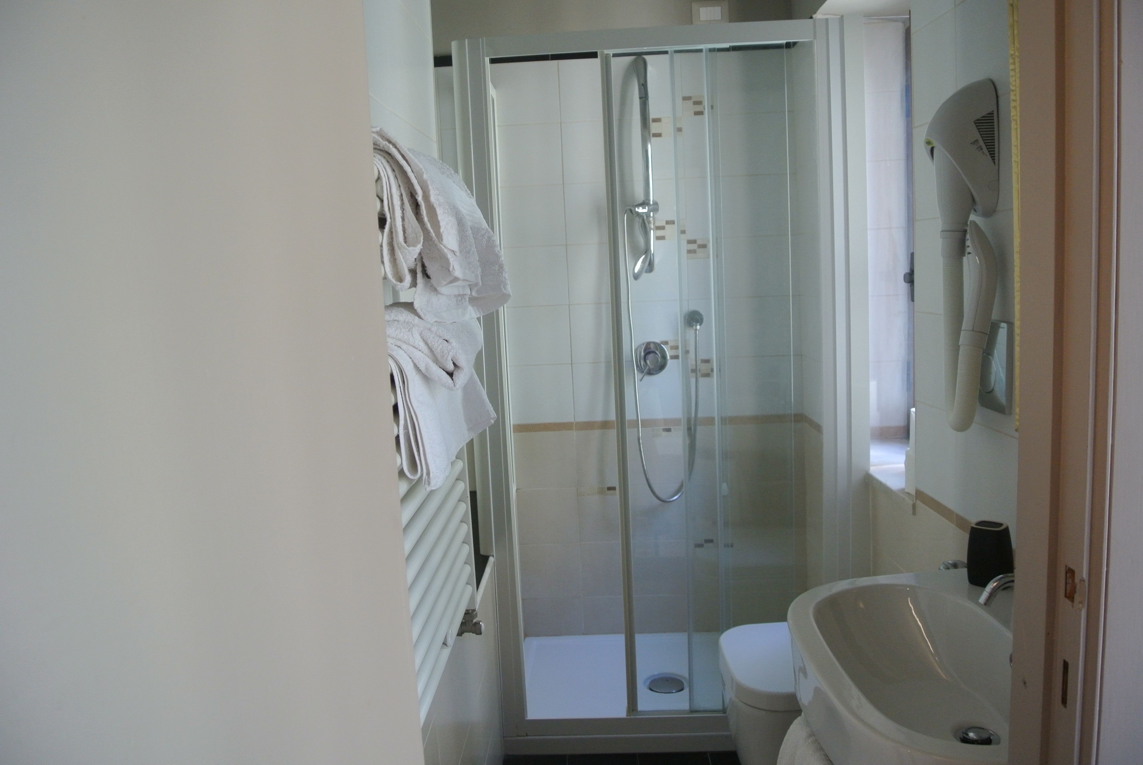 A bathroom with a glass-enclosed shower, a sink, and a toilet.