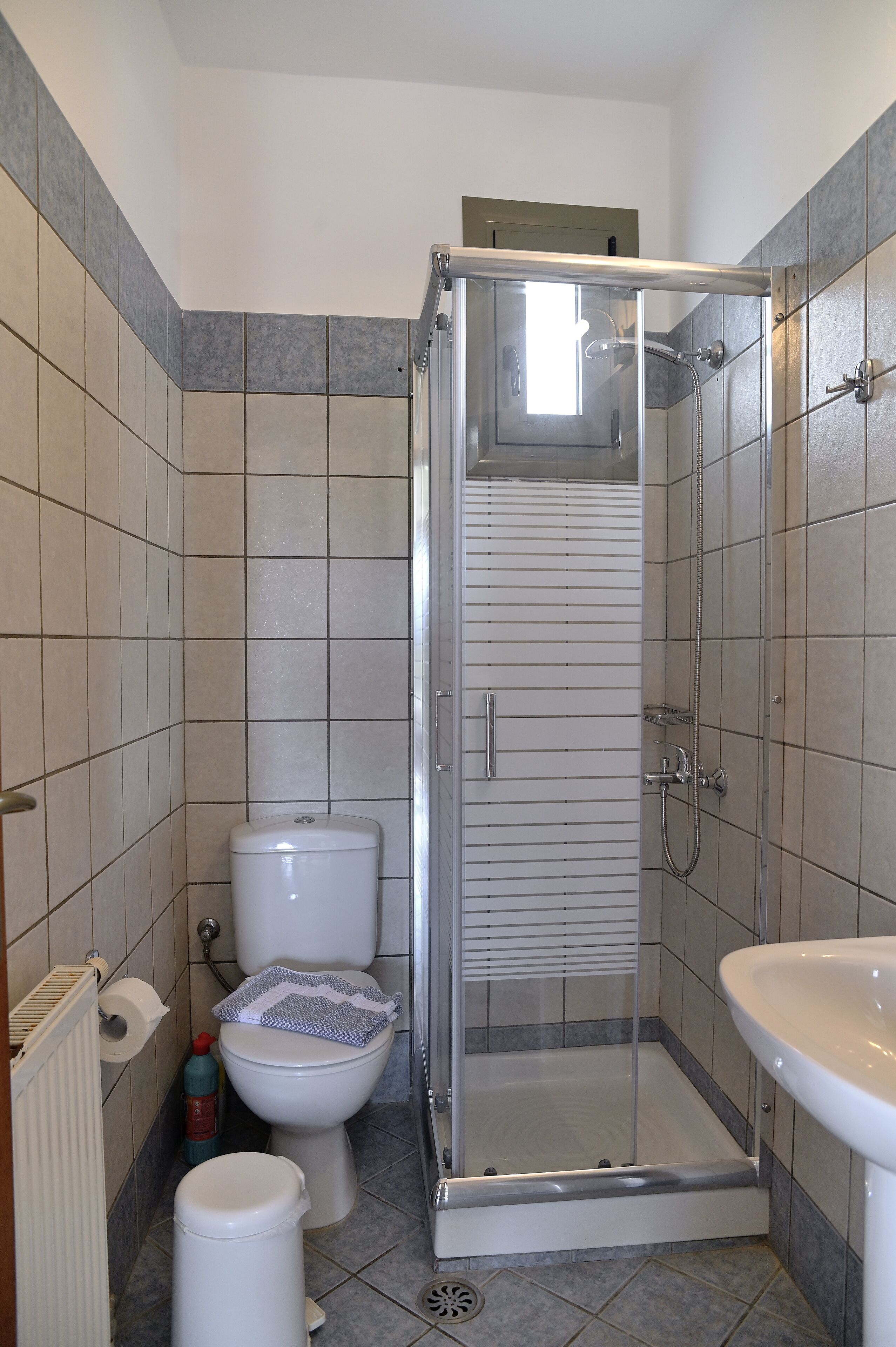 Une salle de bain avec une douche à parois de verre, des toilettes et un lavabo.