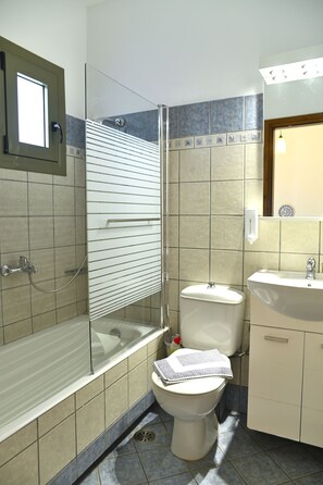 A bathroom with a glass-enclosed shower, a toilet, and a sink.