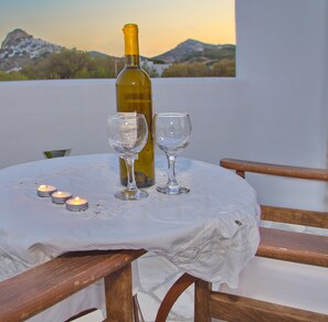 A table with a wine bottle and two glasses, candles, and a view of mountains in the background.