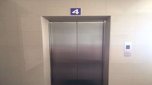 An elevator with a "WELCOME" mat at the entrance, a number "4" sign above it, and a digital control panel on the wall. - CK Residence (Hat Yai)