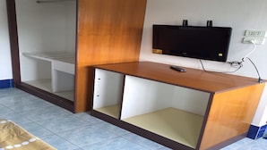 A room with a wooden desk, a TV mounted on the wall, and a wardrobe with a mirror. - CK Residence (Hat Yai)