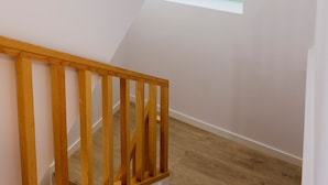 Una scala in legno con un muro bianco e un lucernario.