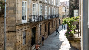 Un vicolo stretto con edifici in pietra, un percorso pedonale e alcune persone che passeggiano.