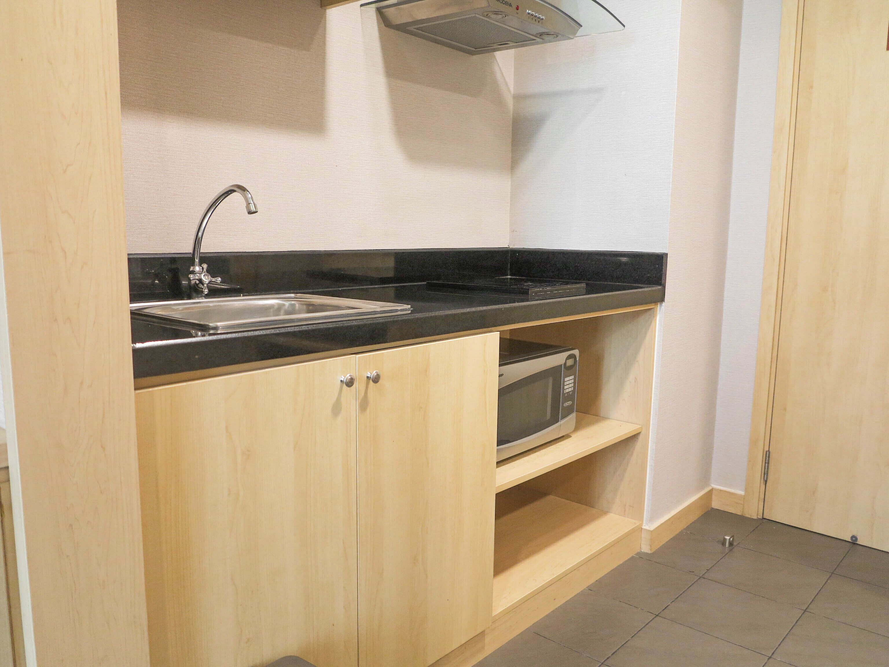 A compact kitchen with a sink, a microwave, and a black countertop.