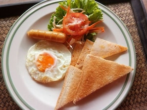 Une assiette avec un œuf au plat, une crevette grillée, une tranche de pain grillé et une salade.
