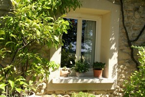 A window with a stone wall, two potted plants, and a small window ledge.