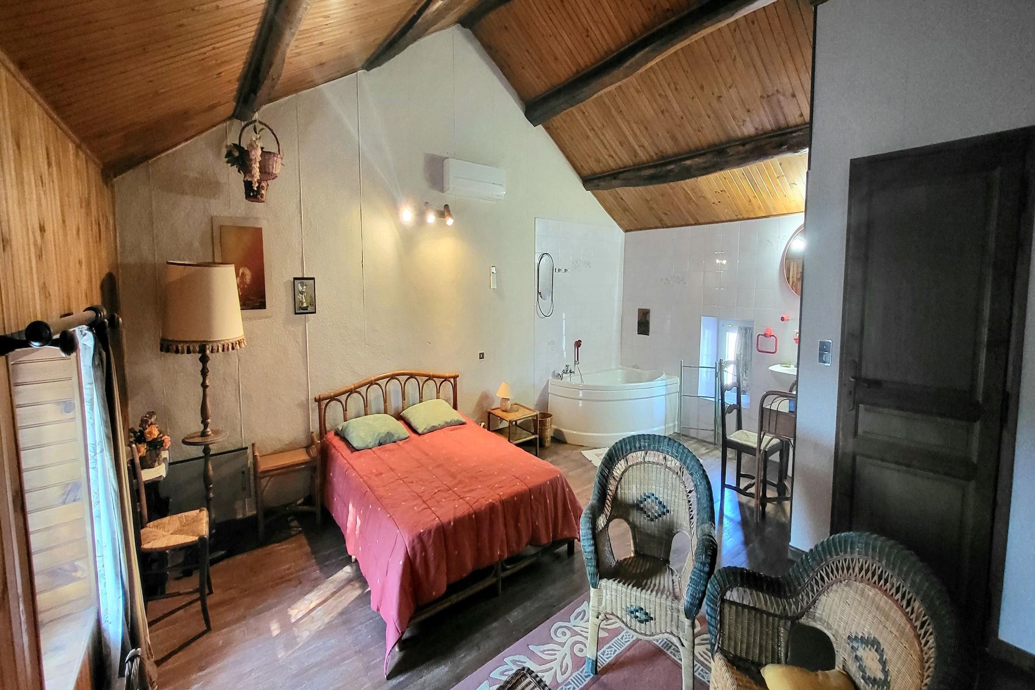 Une chambre à coucher comprenant un lit, une table de chevet et une lampe, ainsi qu’une salle de bain avec une baignoire et un lavabo.