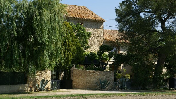 A stone building with a tiled roof, surrounded by trees and a stone wall. - Holiday Home in Provence with Pool & Tennis (Piolenc)
