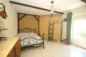 A bedroom with a bed, a dresser, a hanging rack, a ladder, and a window with a view.