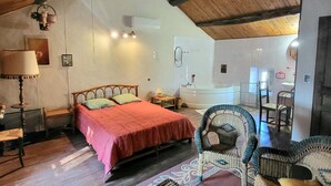 A bedroom with a bed, a nightstand, a lamp, a chair, and a bathroom with a bathtub. - Holiday Home in Provence with Pool & Tennis (Piolenc)