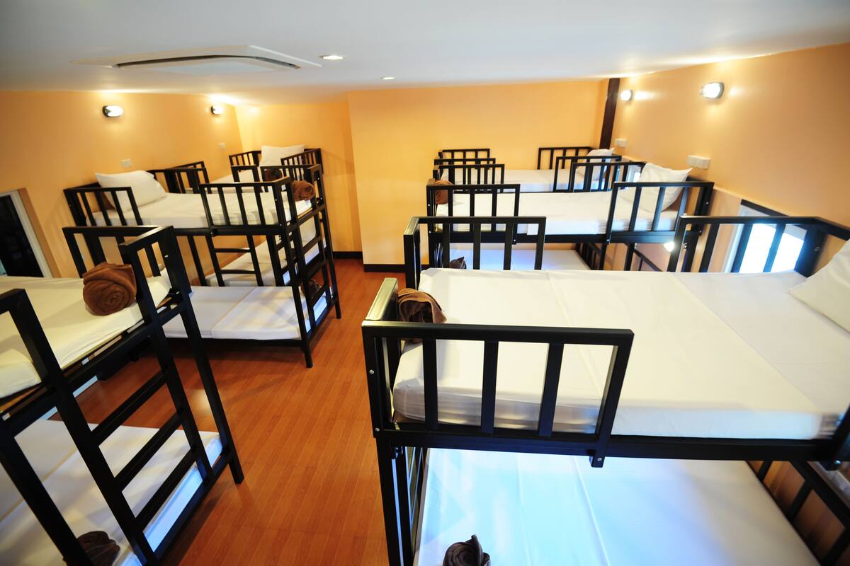 Une chambre de dortoir avec plusieurs lits superposés, des rampes en bois et un plancher en bois.