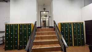 A staircase with wooden steps and metal railings, flanked by rows of green lockers. - Twin Palms Hostel Phi Phi (Ko Phi Phi)