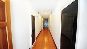 A long, narrow hallway with wooden doors on both sides and a shiny, polished floor. - Twin Palms Hostel Phi Phi (Ko Phi Phi)