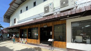 A building with a wooden storefront and large windows. - Twin Palms Hostel Phi Phi (Ko Phi Phi)