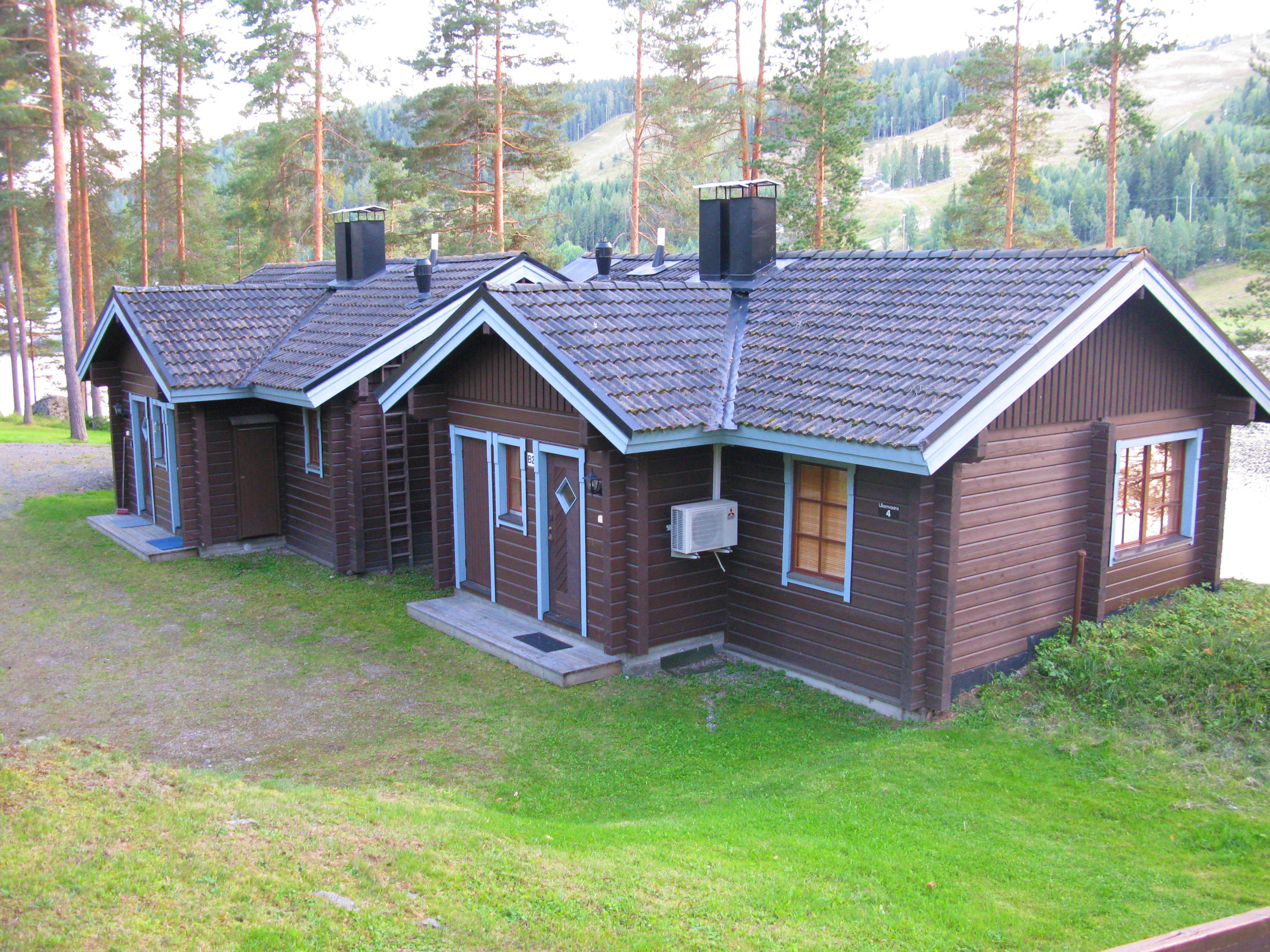 A row of cabins with a sloped roof, a central chimney, and a small porch area.