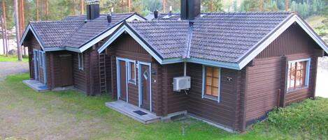 A row of cabins with a sloped roof, a central chimney, and a small porch area.
