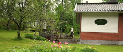 A garden with a variety of flowers and a small brick building with a white exterior and a window.
