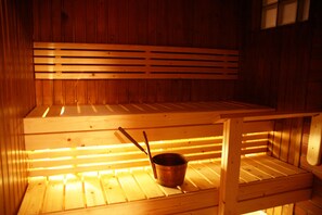 A wooden sauna with benches and a metal bucket. - Villa Prud (Kuopio)