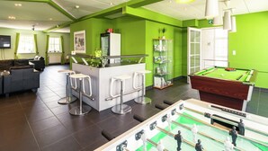 A modern indoor space with a pool table, a foosball table, and a bar area with stools. - Group Escape in Mellier (Mellier)