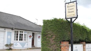 A white building with a sign reading "Remarc Guest House" and a phone number. - Remarc House Stansted (Bishop's Stortford)