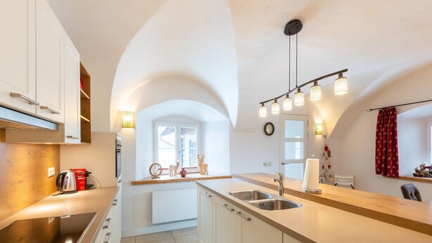 Een moderne keuken met een centraal eiland, roestvrijstalen apparatuur en een gebogen plafond.