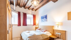 Een slaapkamer met een houten frame, een bed, nachtkastjes en een raam met gordijnen.