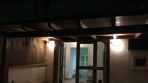 Una entrada tenuemente iluminada con vigas de madera, suelo de baldosas y una puerta que da a un espacio con comedor.