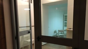 Una habitación moderna con un ventanal que da a un comedor con mesa y sillas blancas.