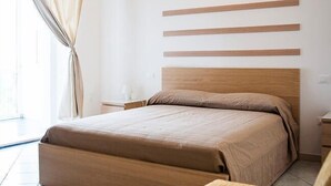 Un dormitorio con cabecera de cama de madera, una colcha grande y una mesita de noche con lámpara.